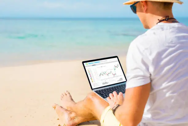 Photo of Man trading cryptocurrencies on the beach.