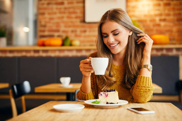 istock Attractive smiling young lady sitting in a cafeteria having cake and coffee 1031313720