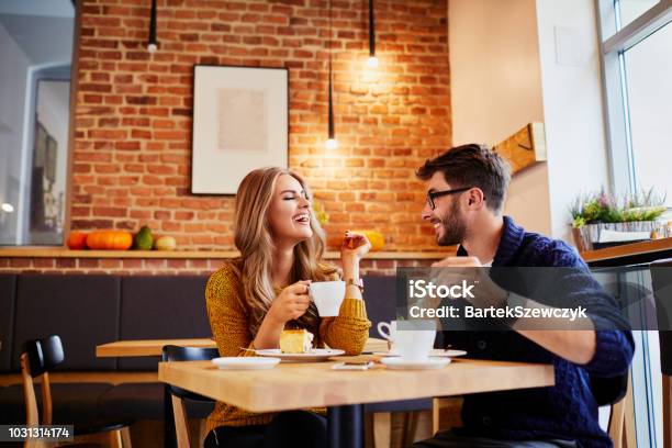 Couple Of Young People Drinking Coffee And Eating Cake In A Stylish Modern Cafeteria Stock Photo - Download Image Now