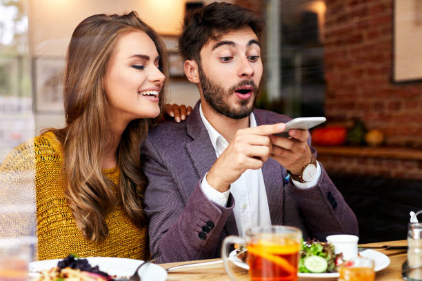 istock Cute cheerful young couple having fun while sitting in a restaurant, taking photos while eating and smiling 1031316954