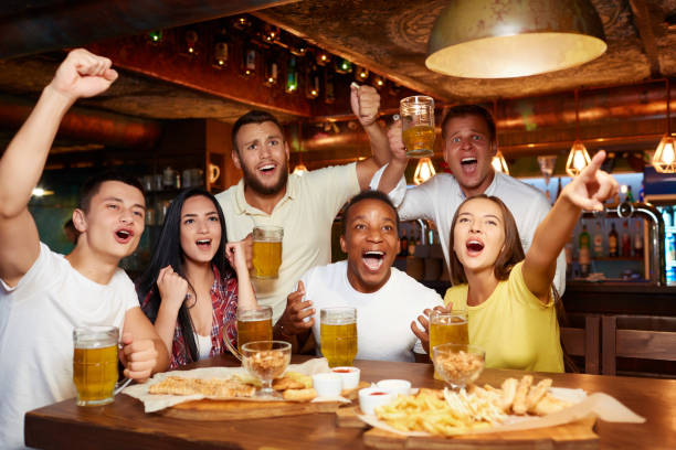 amis heureux s’amuser dans la pub, je regarde le sport à la télévision ensemble. - match international photos et images de collection