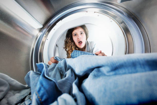 istock Beautiful young woman is shocked, looking into tumble drier 1031318198
