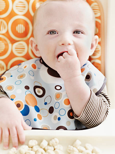 baby eating small cookies - finger in mouth ストックフォトと画像