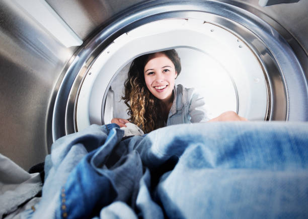 istock Beautiful young woman reaches into tumble drier 1031325830
