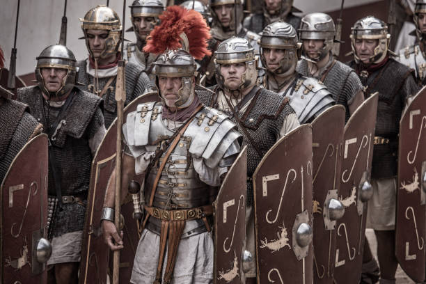 Romans during a public performance Alphen aan den Rijn, Netherlands - July 30, 2018: Large number of male re-enactors dressed as Roman Centurions and soldiers marching in formation during a public performance at Archeon Park in Alphen aan den Rijn, the Netherlands roman centurion stock pictures, royalty-free photos & images