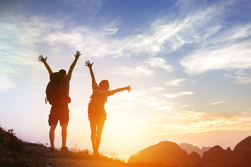 Two happy tourists backpackers greetings sunrise or at mountains top