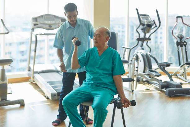 istock Male nurse assisting patient in exercise at gym 1031336908