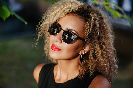 Street fashion - portrait of young beautiful african american afro woman in sunglasses in the city.