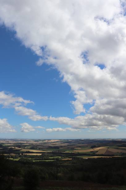 istock Big fluffy white cloud in blue sky over field with gate 1031345036