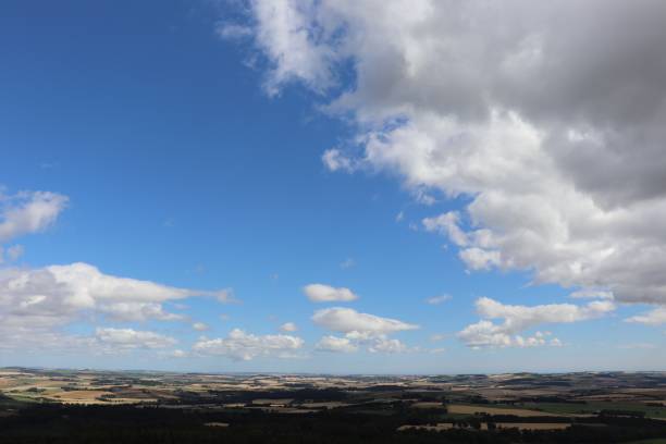 istock Big fluffy white cloud in blue sky over field with gate 1031345040