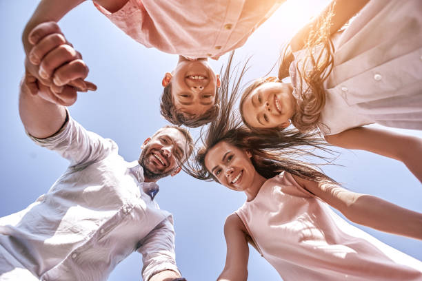 istock Bonding. Family of four standing in circle looking down the camera smiling cheerful bottom view close-up 1031347570