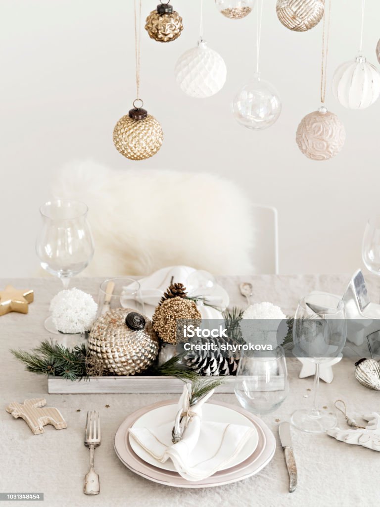 Golden and silver baubles in design of table setting. View of crystal and silver utensil on table set for New Year with shiny golden and silver baubles. Christmas Stock Photo