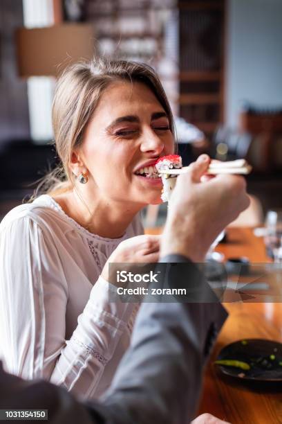Woman Taking A Bite Of Sushi Roll Stock Photo - Download Image Now - Sushi, Eating, Sushi Bar
