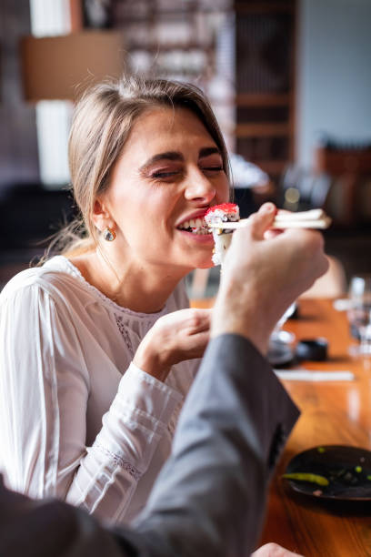 mulher tomando uma mordida de sushi roll - sushi chopsticks sushi bar food - fotografias e filmes do acervo