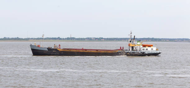 istock Sand dredging boat drawing away from coast shoreline 1031359396