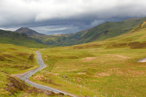 istock Curved winding road between Scottish Glenshee hills with blue clouds on the horizon in Cairngorms National Park 1031359706