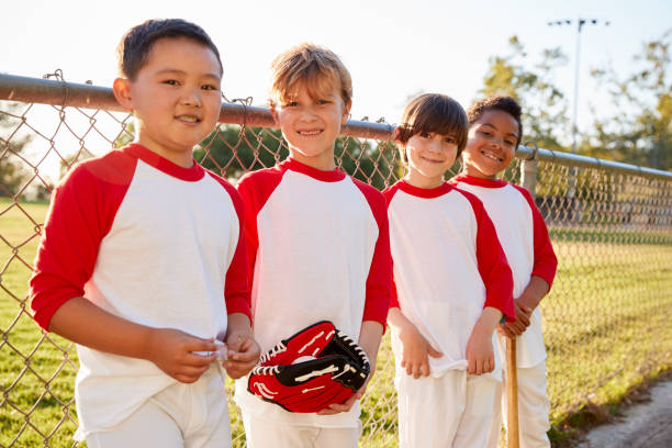 jungen in einem baseball-team mit mitt und bat ich auf kamera - baseballmannschaft stock-fotos und bilder