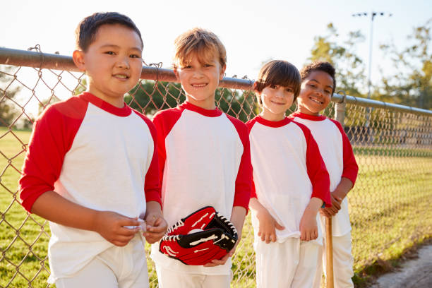 Boys in a baseball team with mitt and bat looking to camera Boys in a baseball team with mitt and bat looking to camera youth baseball and softball league photos stock pictures, royalty-free photos & images