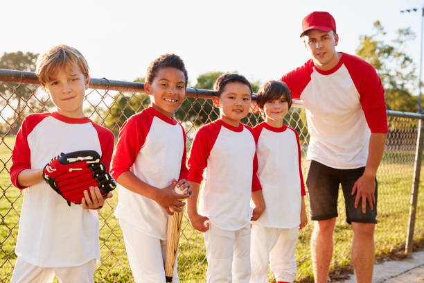 trainer und junge boys in einem baseballteam auf kamera - baseballmannschaft stock-fotos und bilder