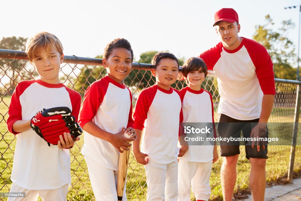 Entraîneur et les jeunes garçons dans une équipe de baseball à la recherche d’appareil photo - Photo de Baseball libre de droits