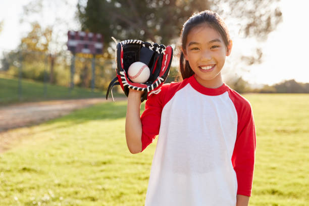 молодая китайская девушка, держащая бейсбол в рукавица смотрит в камеру - baseball glove фотографии стоковые фото и изображения