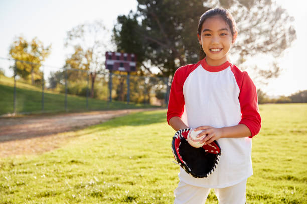 istock Chinese schoolgirl holding baseball and mitt smiling 1031366526