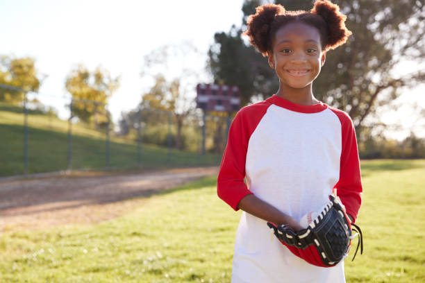 A softball player is captured holding her glove during practice on a sunny field.