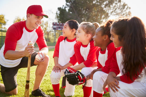 istock Girl baseball team kneeling in a huddle with their coach 1031368756
