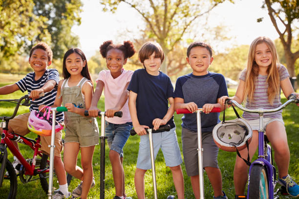 istock Elementary age school kids on bikes and scooters in a park 1031368768