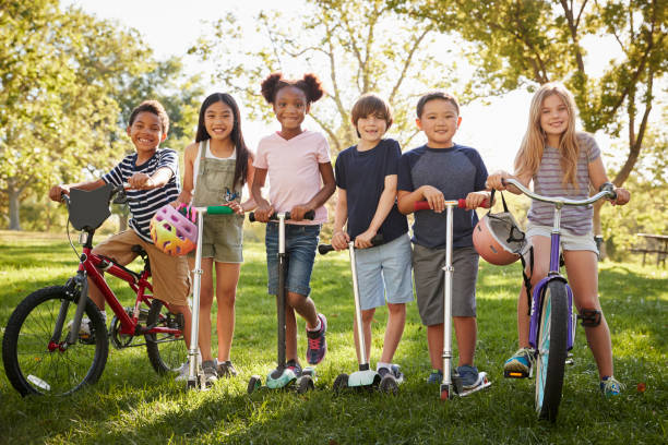 istock School friends on bikes and scooters in a park, full length 1031368774