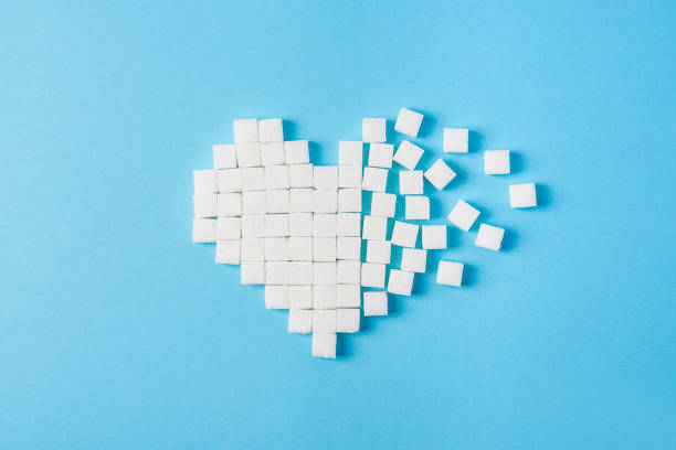 broken heart made of sugar cubes on a blue background stock photo