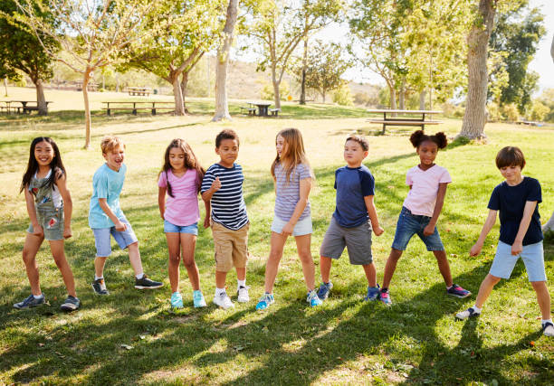 公園で遊ぶ小学生の多民族のグループ - child dancing ethnic outdoors ストックフォ�トと画像