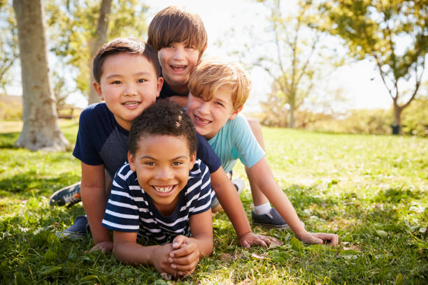 istock Four schoolboys lying on each other in a field, portrait 1031375996