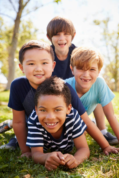 Four schoolboys lying on each other in a park, portrait Four schoolboys lying on each other in a park, portrait only boys stock pictures, royalty-free photos & images