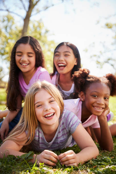 Four schoolgirls lying on each other in a field, close up Four schoolgirls lying on each other in a field, close up preadolescents stock pictures, royalty-free photos & images