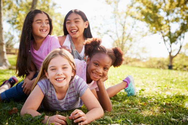 istock Four schoolgirls lying on each other in a field, laughing 1031376124
