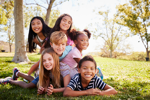 Grupo multiétnico de niños acostado uno al otro en un parque photo