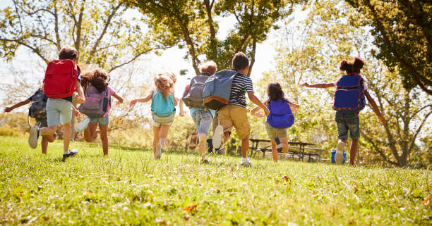 istock Group of schoolchildren running in a field, back view 1031376234
