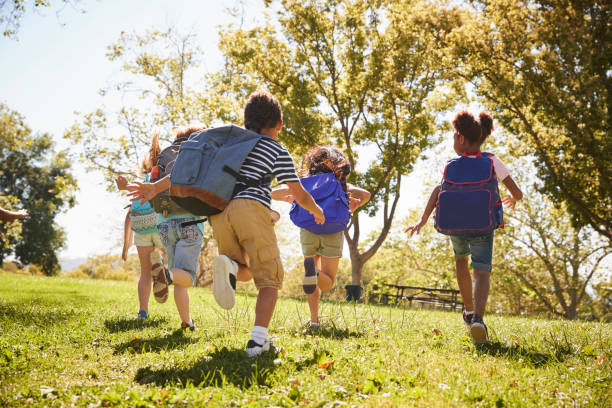 Five school kids running in a field, back view, close up Five school kids running in a field, back view, close up children school stock pictures, royalty-free photos & images