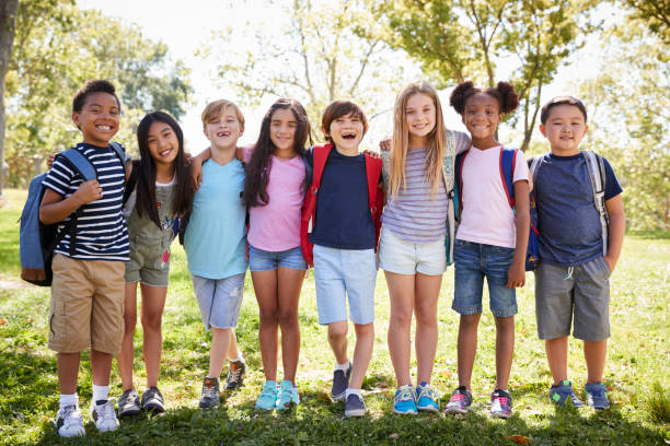 istock School kids stand embracing  in a row  outdoors, full length 1031376380