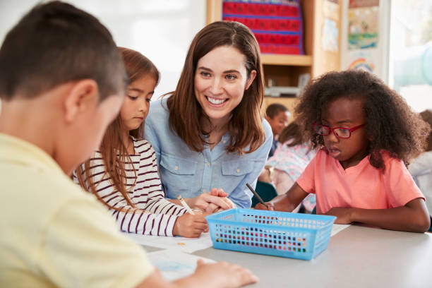 Female elementary school teacher and kids in class, close up Female elementary school teacher and kids in class, close up small group of people stock pictures, royalty-free photos & images