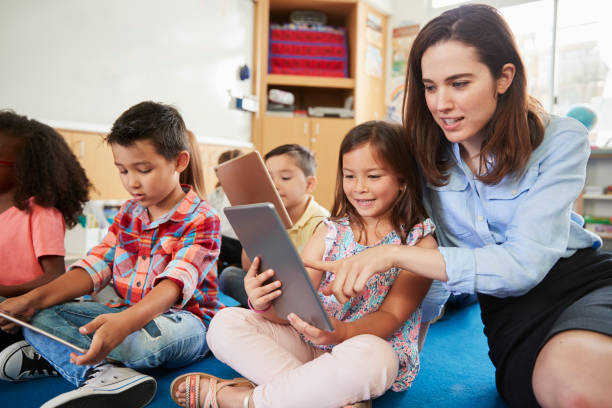 istock Teacher helps girl in elementary class with tablet computers 1031377560