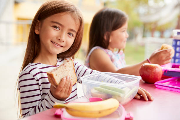 istock Elementary school girls eating at school lunch table 1031378086