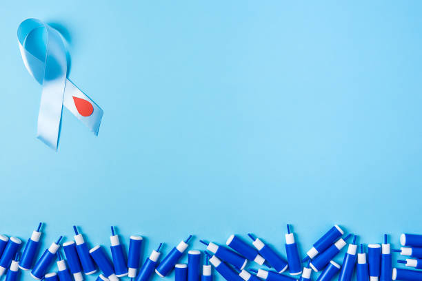 blue ribbon awareness with red blood drop and line of lancets on a blue background, World diabetes day stock photo