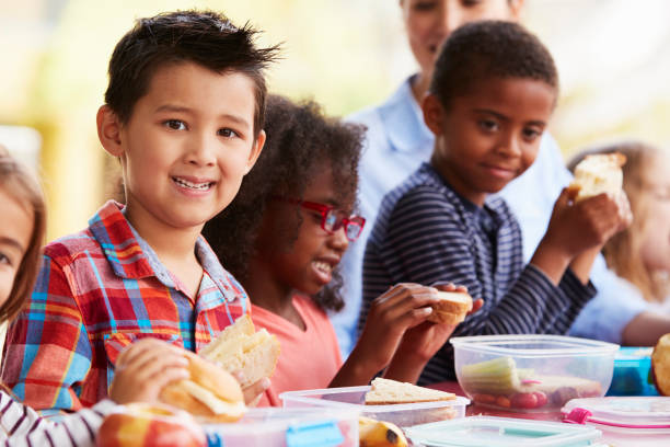 istock School kids eating packed lunches together at a table 1031379468