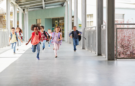 Elementary school kids running to camera in school corridor
