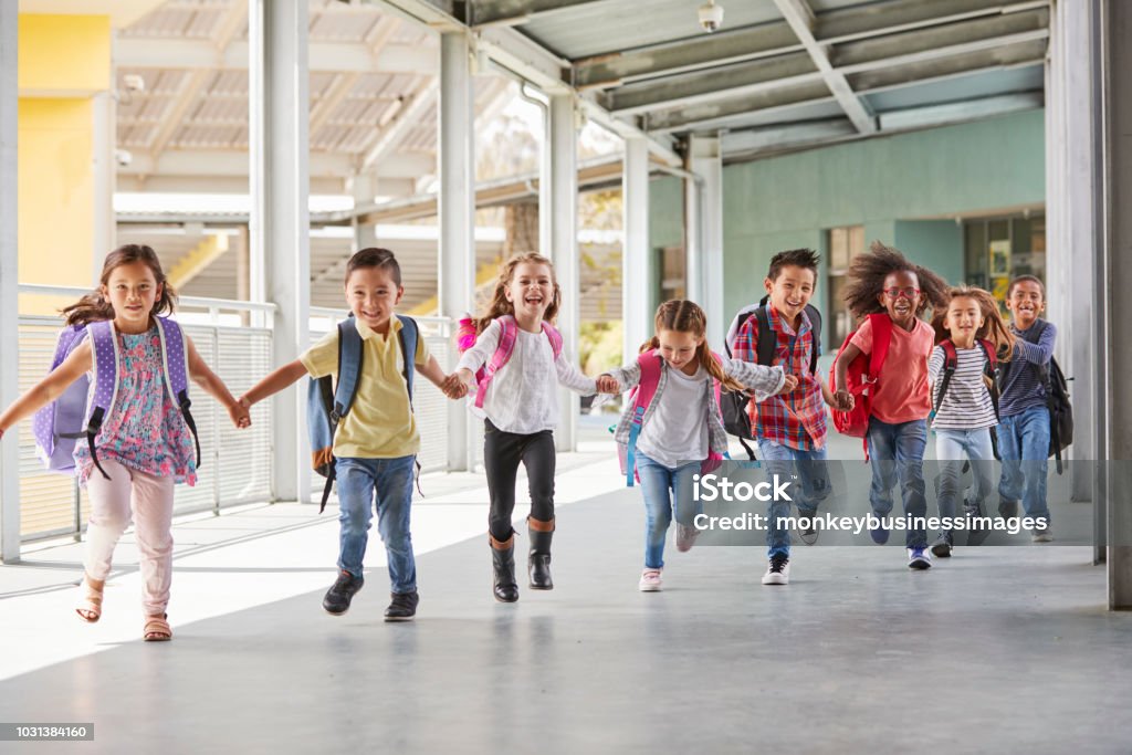 Primary school kids run holding hands in corridor, close up Child Stock Photo