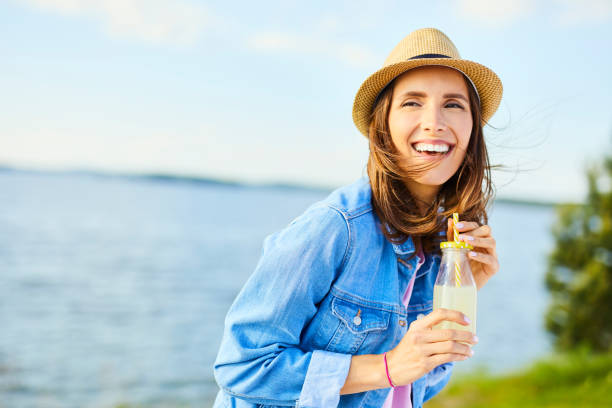 Joyful woman having fun drinking lemonade outdoors