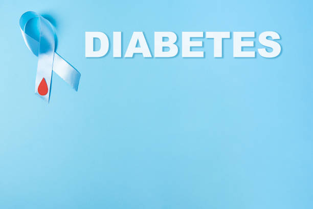inscription diabetes and blue ribbon awareness with red blood drop on a blue background, world diabetes day stock photo