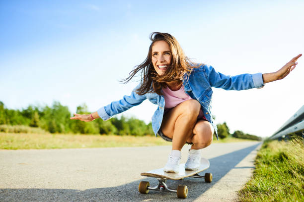 Smiling woman riding longboard in countryside during summer